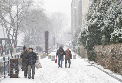 People walking on snow covered city during winter