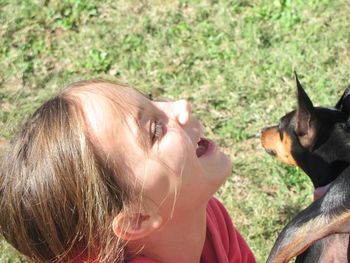 Smiling girl with miniature pinscher on field