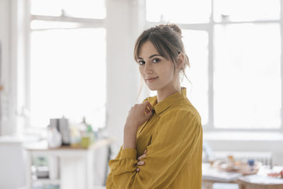 Portrait of a young woman at home, wearing a yellow blouse