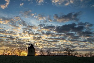 Traditional windmill on field against sky at sunset