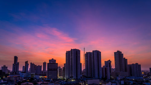 Modern buildings against sky during sunset