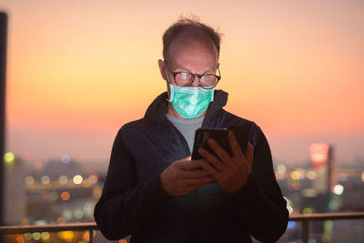 Portrait of man using mobile phone against sunset sky