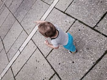 Tilt shot of toddler standing on footpath