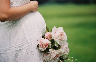 Midsection of pregnant woman with rose flower bouquet