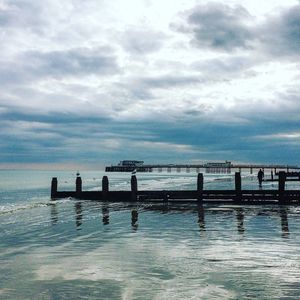 Pier on sea against cloudy sky