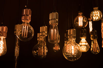 Close-up of illuminated light bulb hanging at night