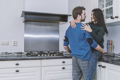 Young couple embracing in kitchen at home