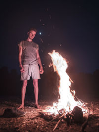 Portrait of man standing by campfire at night