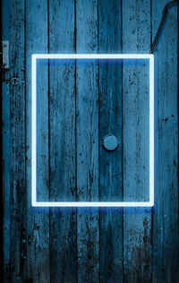 Neon glowing frame on the background of a wooden blue cracked wall, night