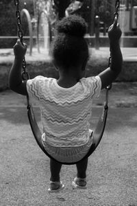 Rear view of girl swinging at playground