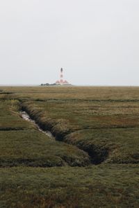 Lighthouse on field against sky