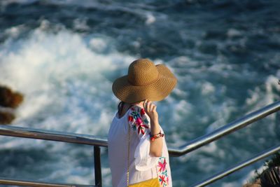 Rear view of woman photographing against sea