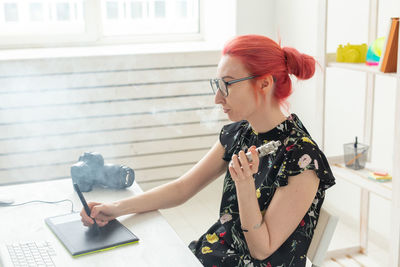 Young woman using phone while sitting on table