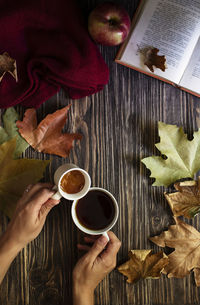 Cropped image of hand holding coffee cup on table