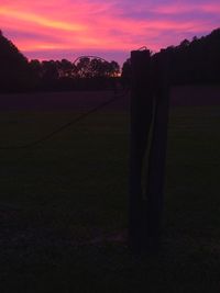 Silhouette trees on field against sky at sunset