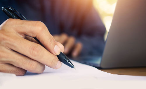 Midsection of woman writing in book