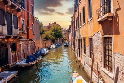 Canal amidst buildings in city against sky