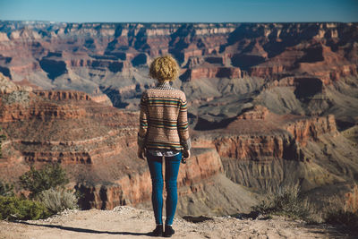 Rear view of woman standing on rock formation