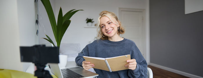 Portrait of young woman using mobile phone while standing at home