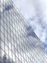 Low angle view of glass building against cloudy sky