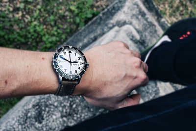 Close-up of hand holding clock against blurred background