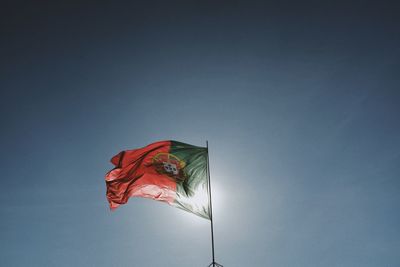 Low angle view of flag waving against sky during sunny day