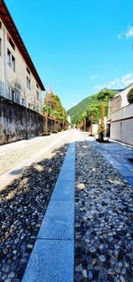 Surface level of footpath by buildings against blue sky