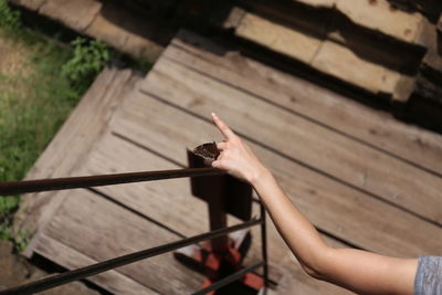 Cropped hand of woman standing by fence