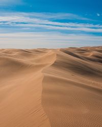 Scenic view of desert dunes against blue sky