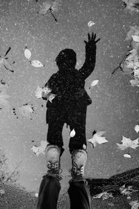 Low section boy standing over puddle on street