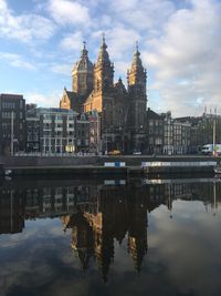 Buildings by river in city against sky