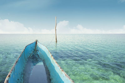 Weathered boat moored at sea against sky