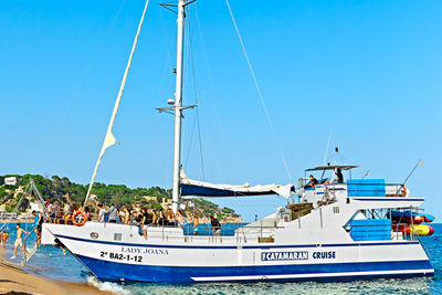 Boats moored at harbor against clear blue sky