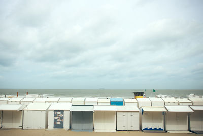 Hooded chairs on beach against sky