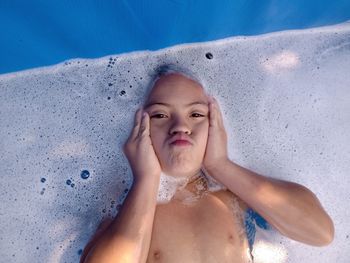 Portrait of shirtless boy lying in water