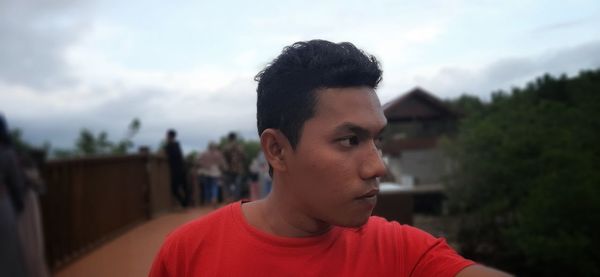 Portrait of young man looking away against sky