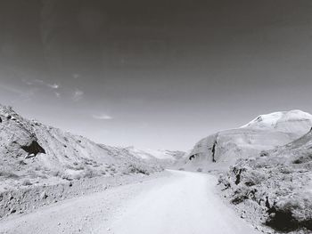 Road amidst snowcapped mountains against sky