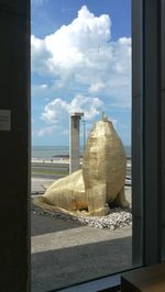 Sculpture by sea against sky seen through window