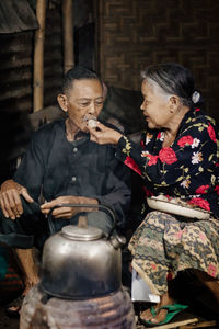 Side view of old man and woman sitting at kitchen