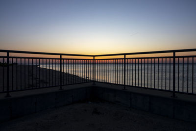 Bridge over sea against clear sky during sunset