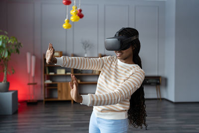 Young astonished afro woman testing vr goggles at first time at home. cyberspace, vr game concept