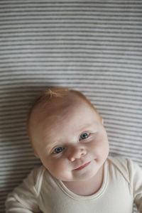 Overhead portrait of baby boy lying on bed