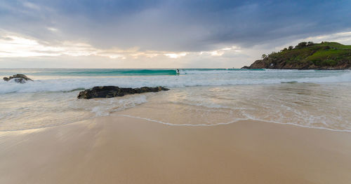 Scenic view of beach against cloudy sky