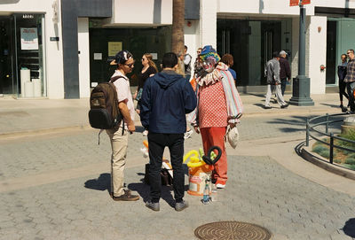 Rear view of people walking on street in city