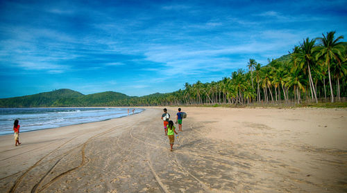 People walking on beach against sky