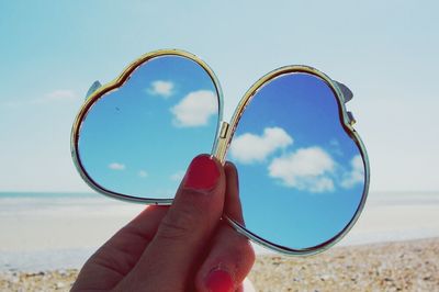 Close-up of cropped hand holding stick against clear sky