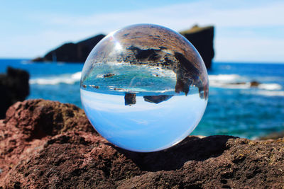 Close-up of water on rock at beach against sky