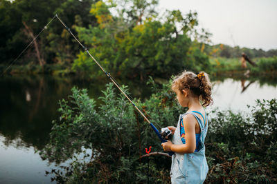 Young girl wearing swim suit fishing in creek during summer