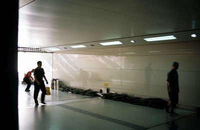 Rear view of people walking on illuminated corridor