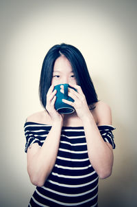 Portrait of beautiful woman holding camera over white background